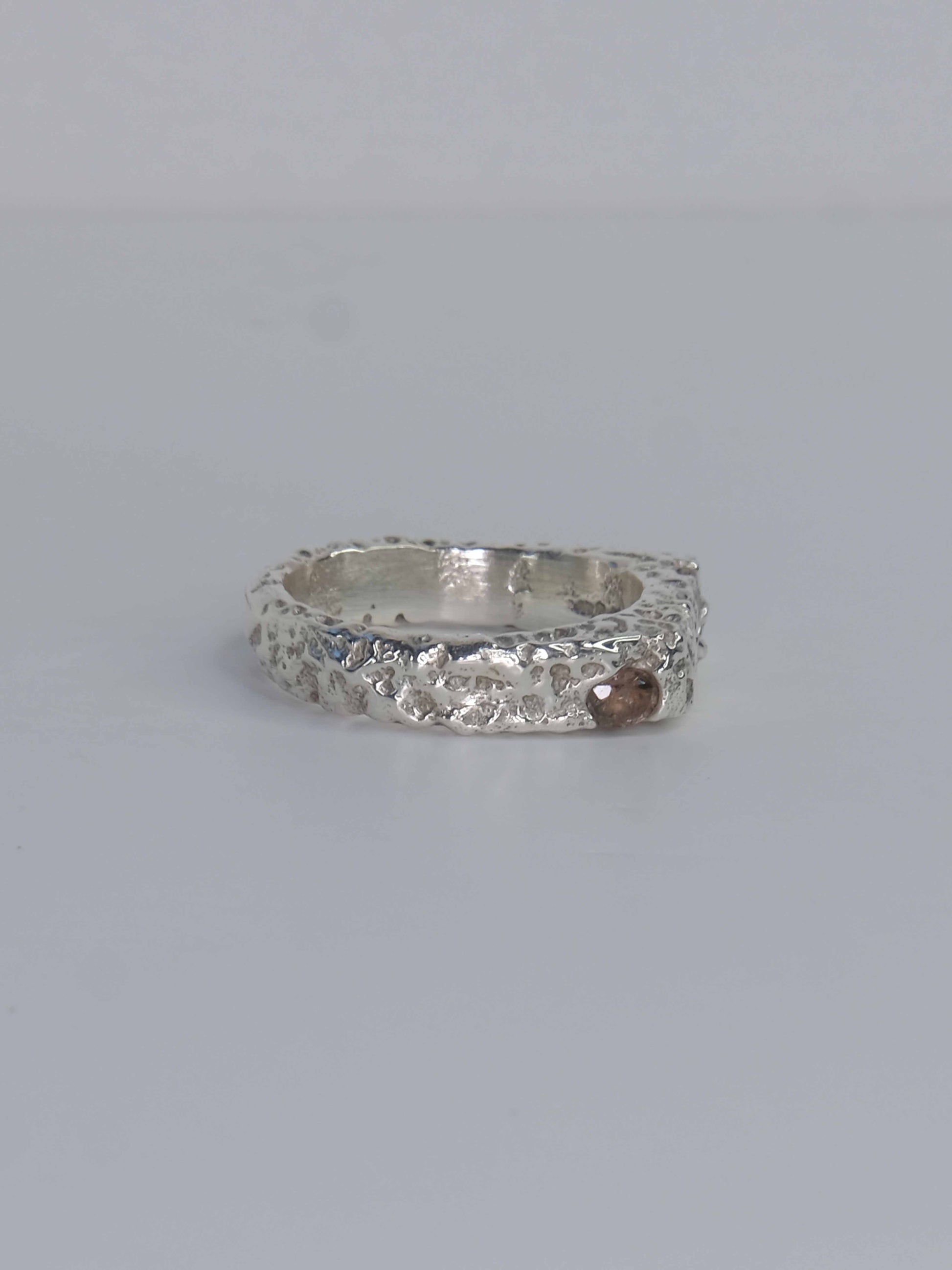 Handgefertigter Dune Siegelring aus 925 Sterling-Silber mit strukturierter Oberfläche in schlanker Form, durch Sandguss gefertigt und mit zwei grünen und auburn braunen Saphiren – designed und made in Berlin.
