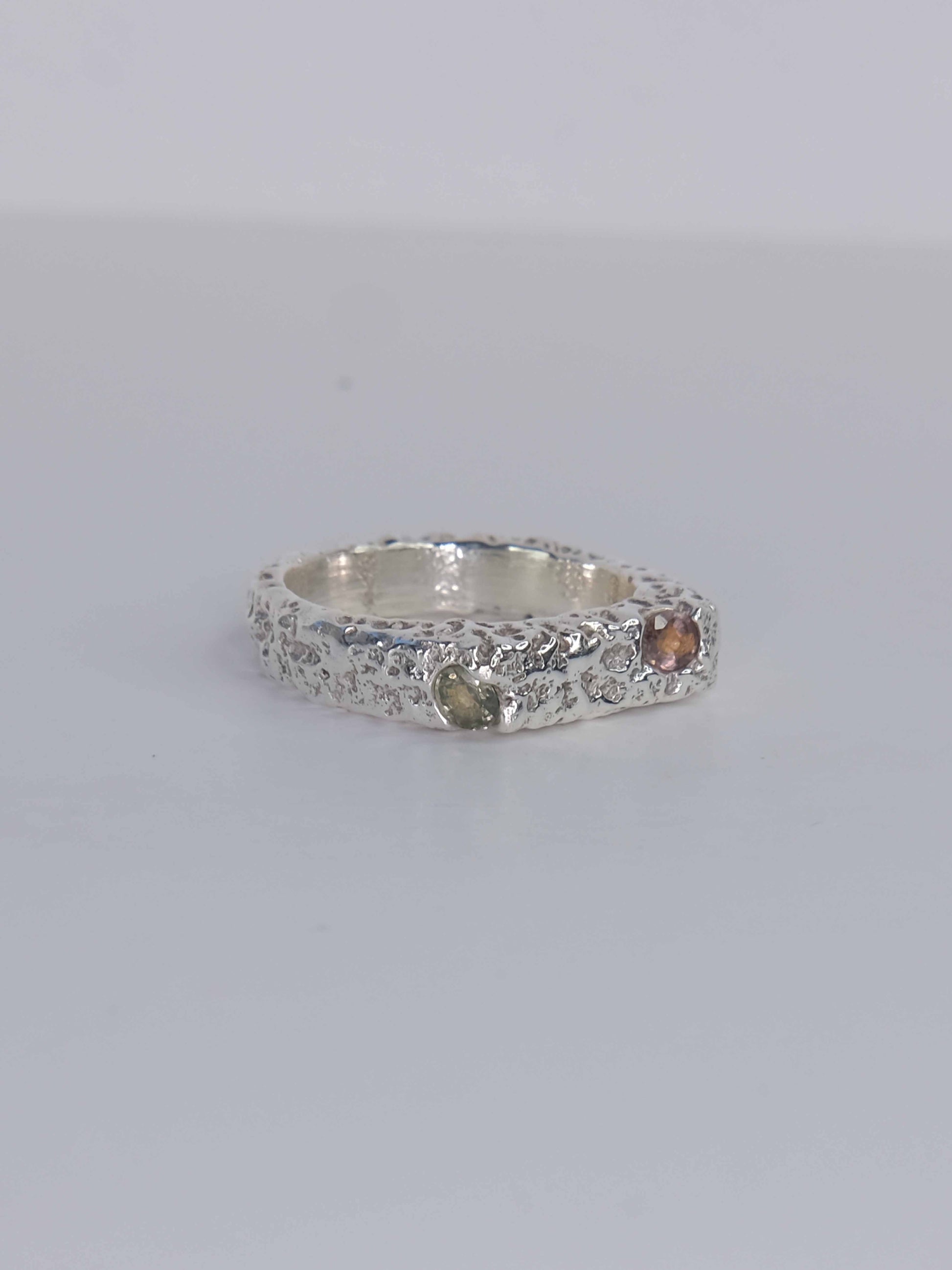 Handgefertigter Dune Siegelring aus 925 Sterling-Silber mit strukturierter Oberfläche in schlanker Form, durch Sandguss gefertigt und mit zwei grünen und auburn braunen Saphiren – designed und made in Berlin.