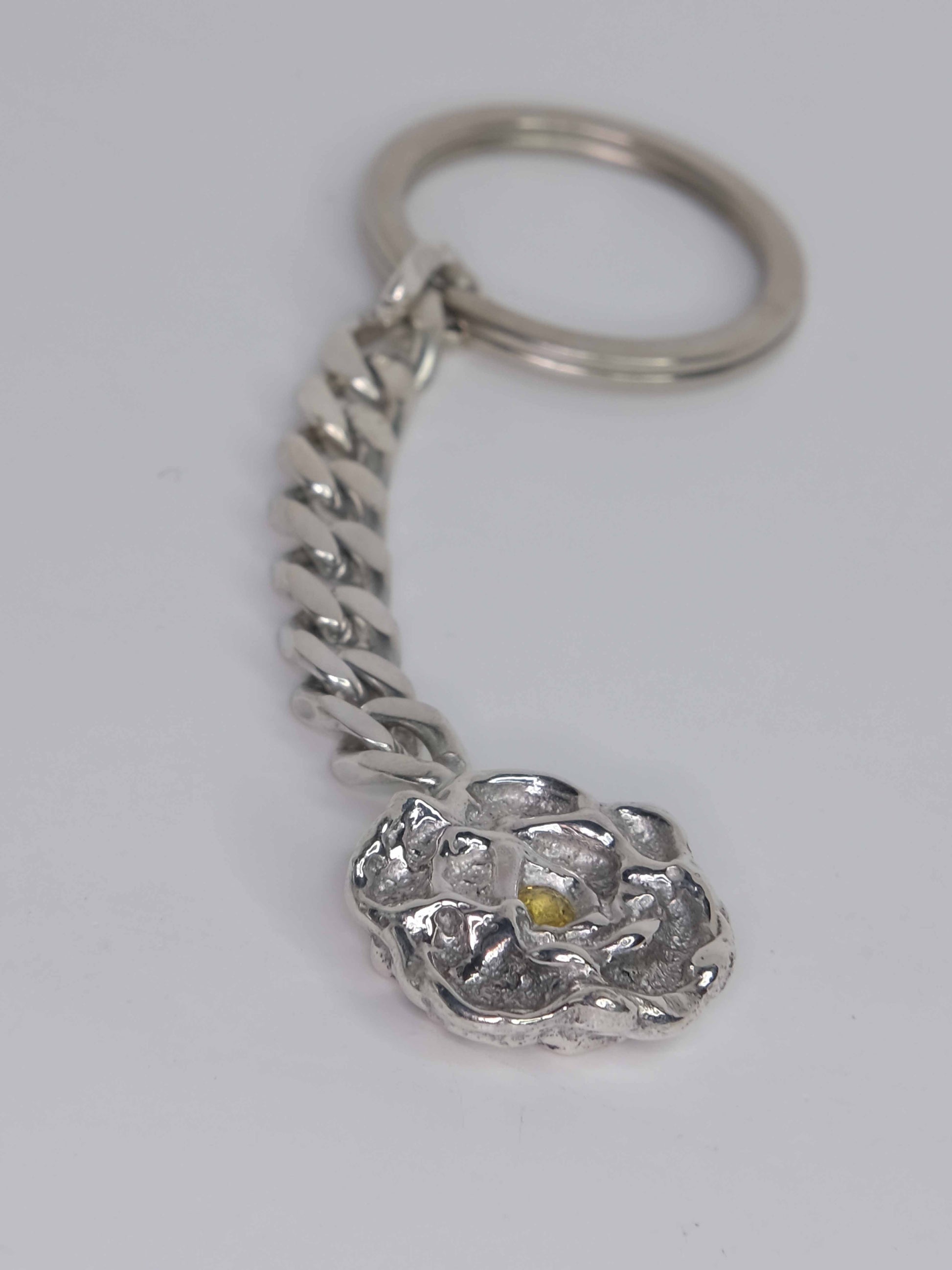 Handgefertigter Schlüsselanhänger aus 925 Sterling-Silber mit wachsmodellierten Blütenblättern, durch Sandguss gefertigt, und gelbem Saphir – designed und made in Berlin.