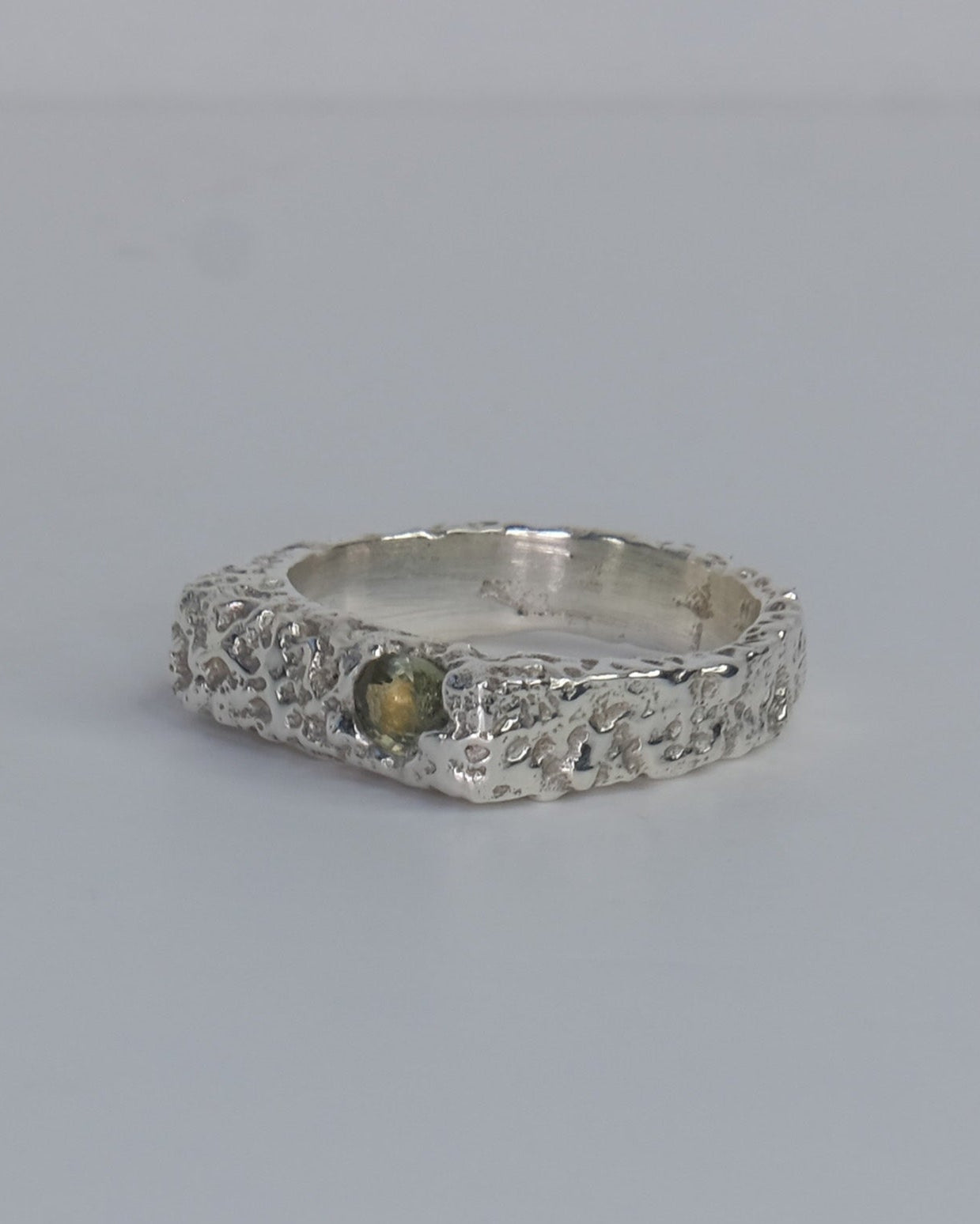 Handgefertigter Dune Siegelring aus 925 Sterling-Silber mit strukturierter Oberfläche in schlanker Form, durch Sandguss gefertigt und mit zwei grünen und auburn braunen Saphiren – designed und made in Berlin.