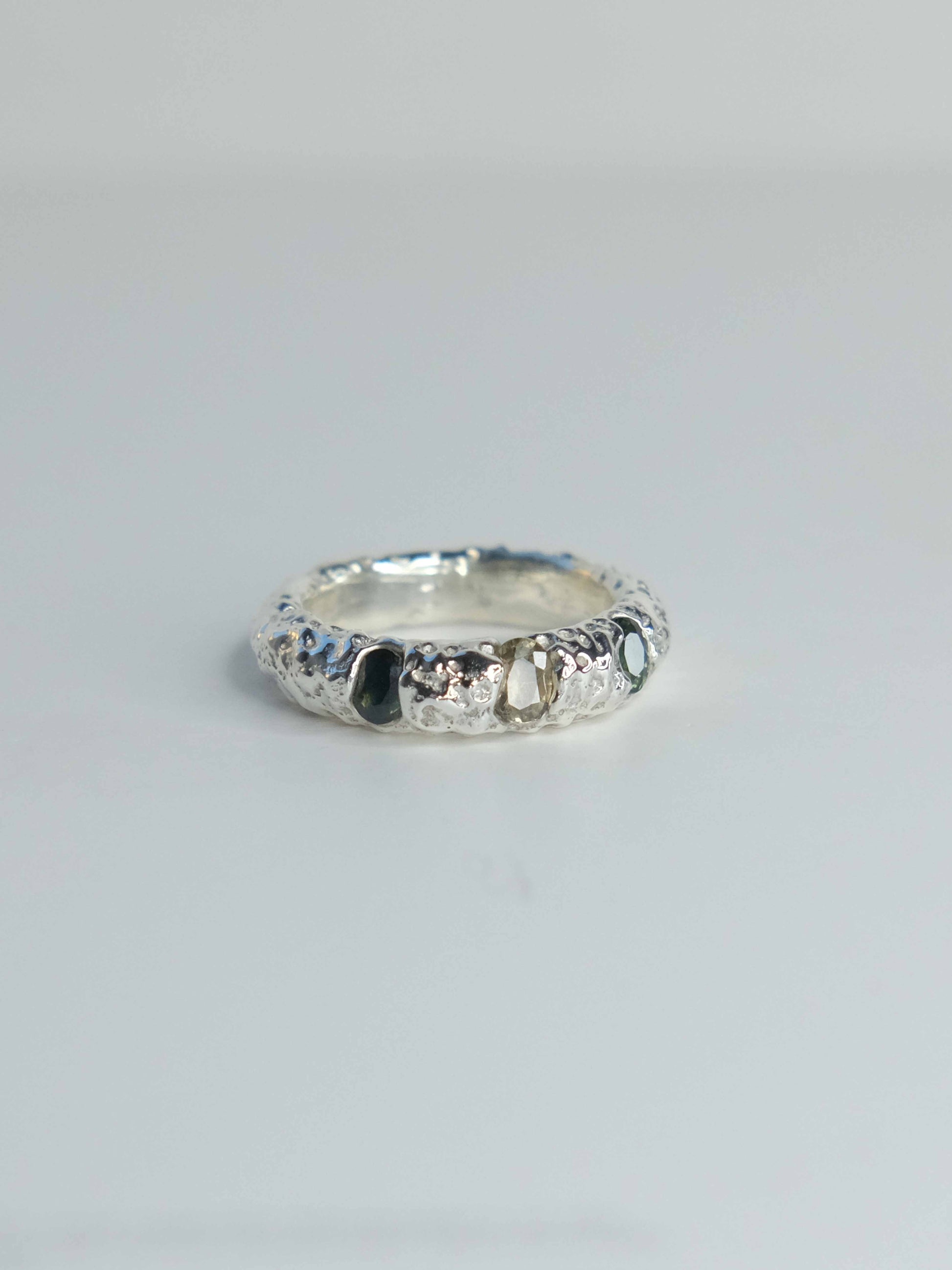 Handgefertigter Ring aus 925 Sterling-Silber strukturierter Oberfläche, durch Sandguss gefertigt, und drei grünen Saphiren – designed und made in Berlin.