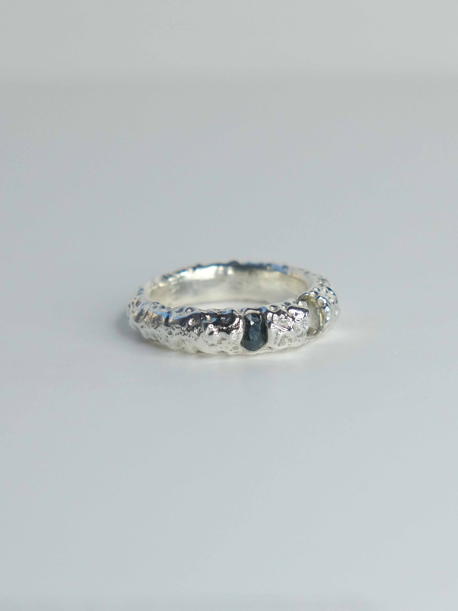 Handgefertigter Ring aus 925 Sterling-Silber strukturierter Oberfläche, durch Sandguss gefertigt, und drei grünen Saphiren – designed und made in Berlin.