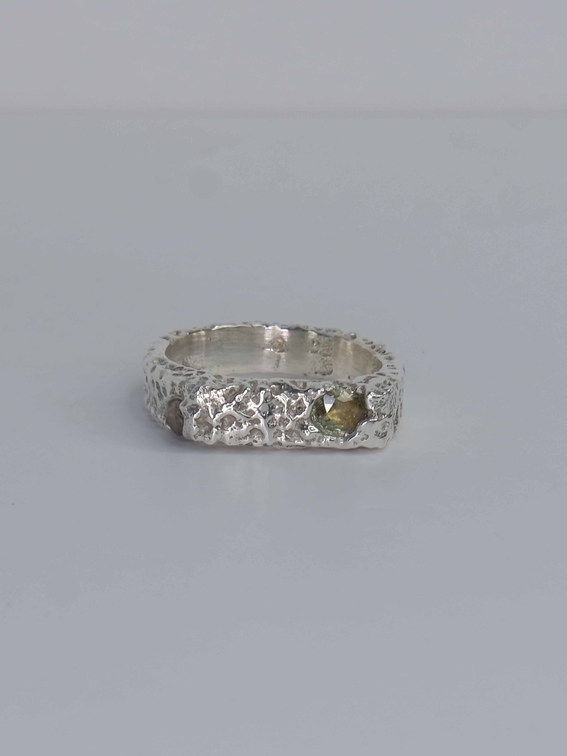 Handgefertigter Dune Siegelring aus 925 Sterling-Silber mit strukturierter Oberfläche in schlanker Form, durch Sandguss gefertigt und mit zwei grünen und auburn braunen Saphiren – designed und made in Berlin.