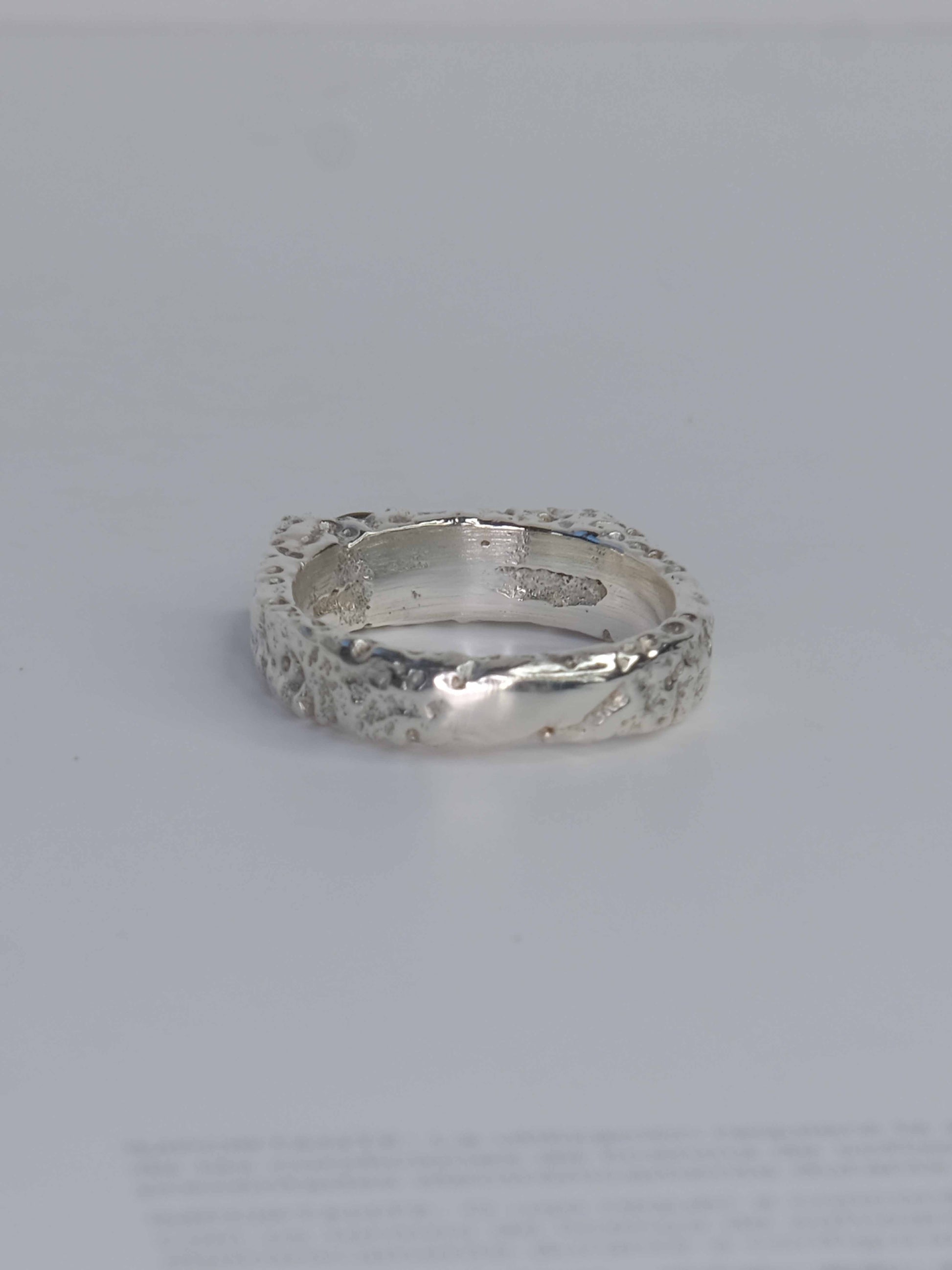Handgefertigter Dune Siegelring aus 925 Sterling-Silber mit strukturierter Oberfläche in schlanker Form, durch Sandguss gefertigt und mit zwei grünen und auburn braunen Saphiren – designed und made in Berlin.