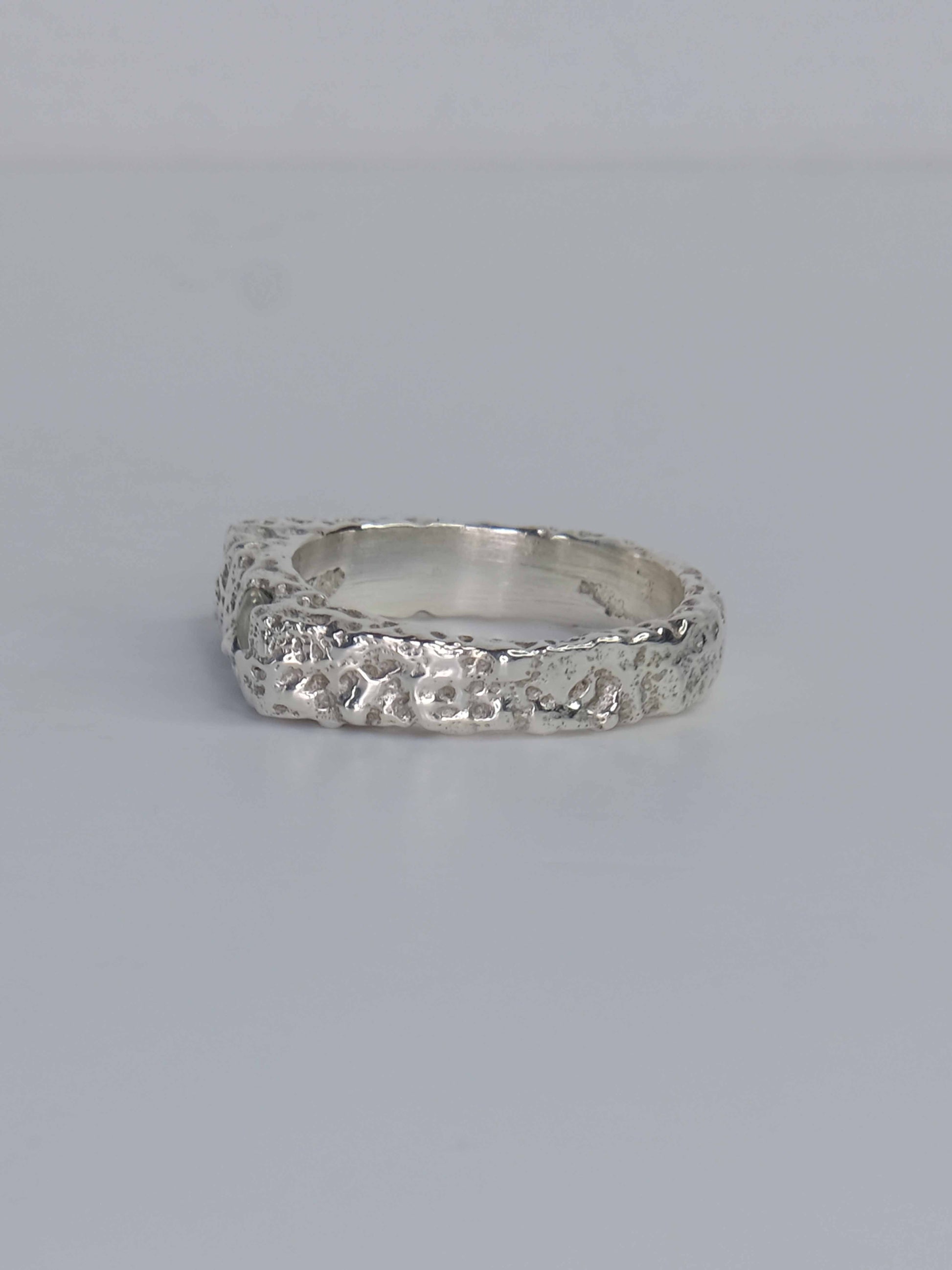Handgefertigter Dune Siegelring aus 925 Sterling-Silber mit strukturierter Oberfläche in schlanker Form, durch Sandguss gefertigt und mit zwei grünen und auburn braunen Saphiren – designed und made in Berlin.