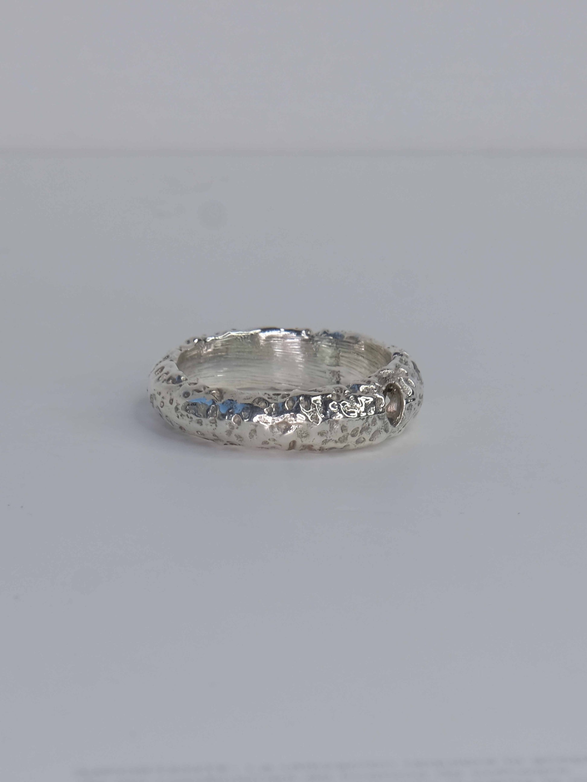 Handgefertigter Ring aus 925 Sterling-Silber strukturierter Oberfläche, durch Sandguss gefertigt, und drei grünen und roten Saphiren – designed und made in Berlin.