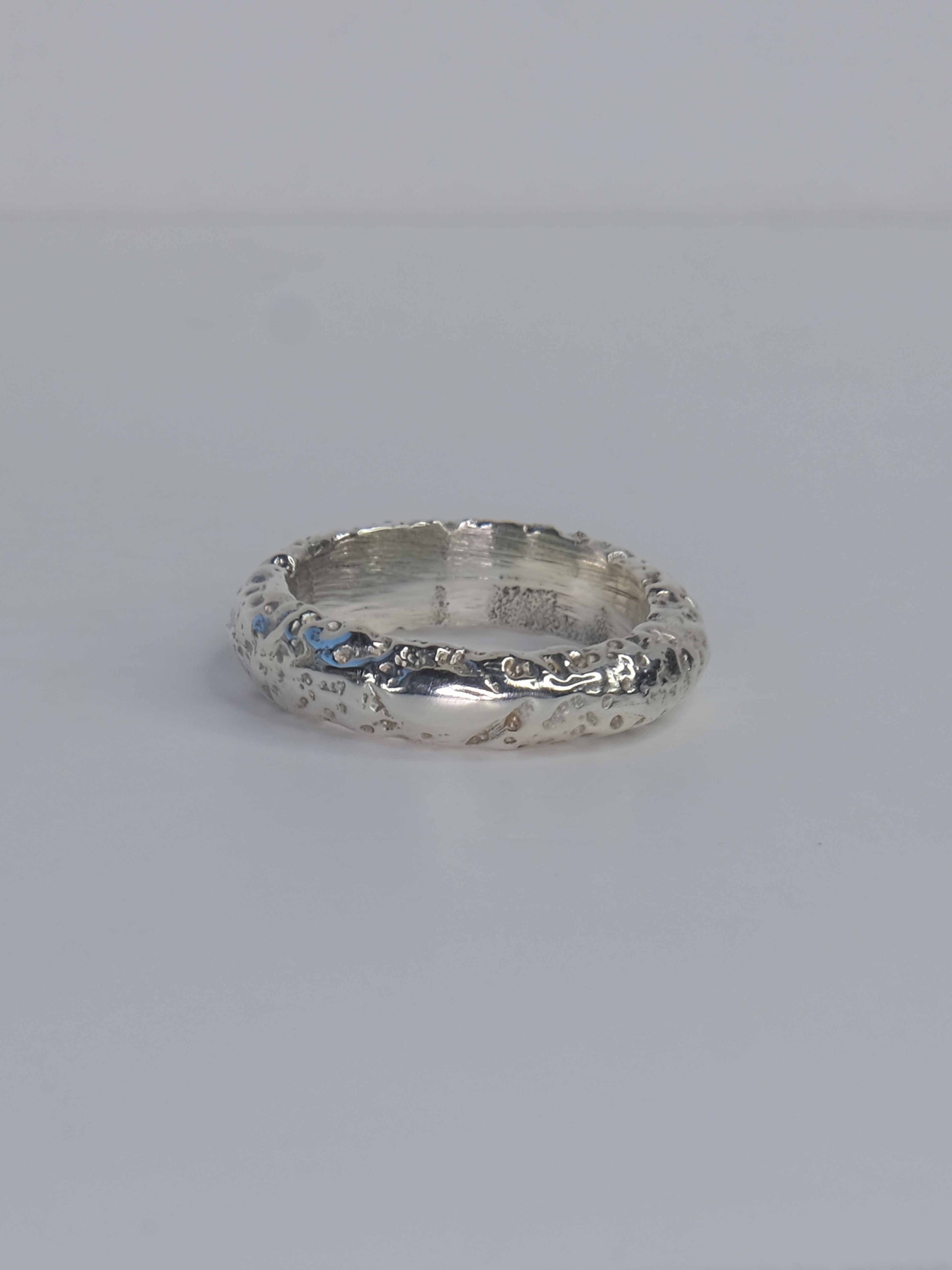 Handgefertigter Ring aus 925 Sterling-Silber strukturierter Oberfläche, durch Sandguss gefertigt, und drei grünen und roten Saphiren – designed und made in Berlin.