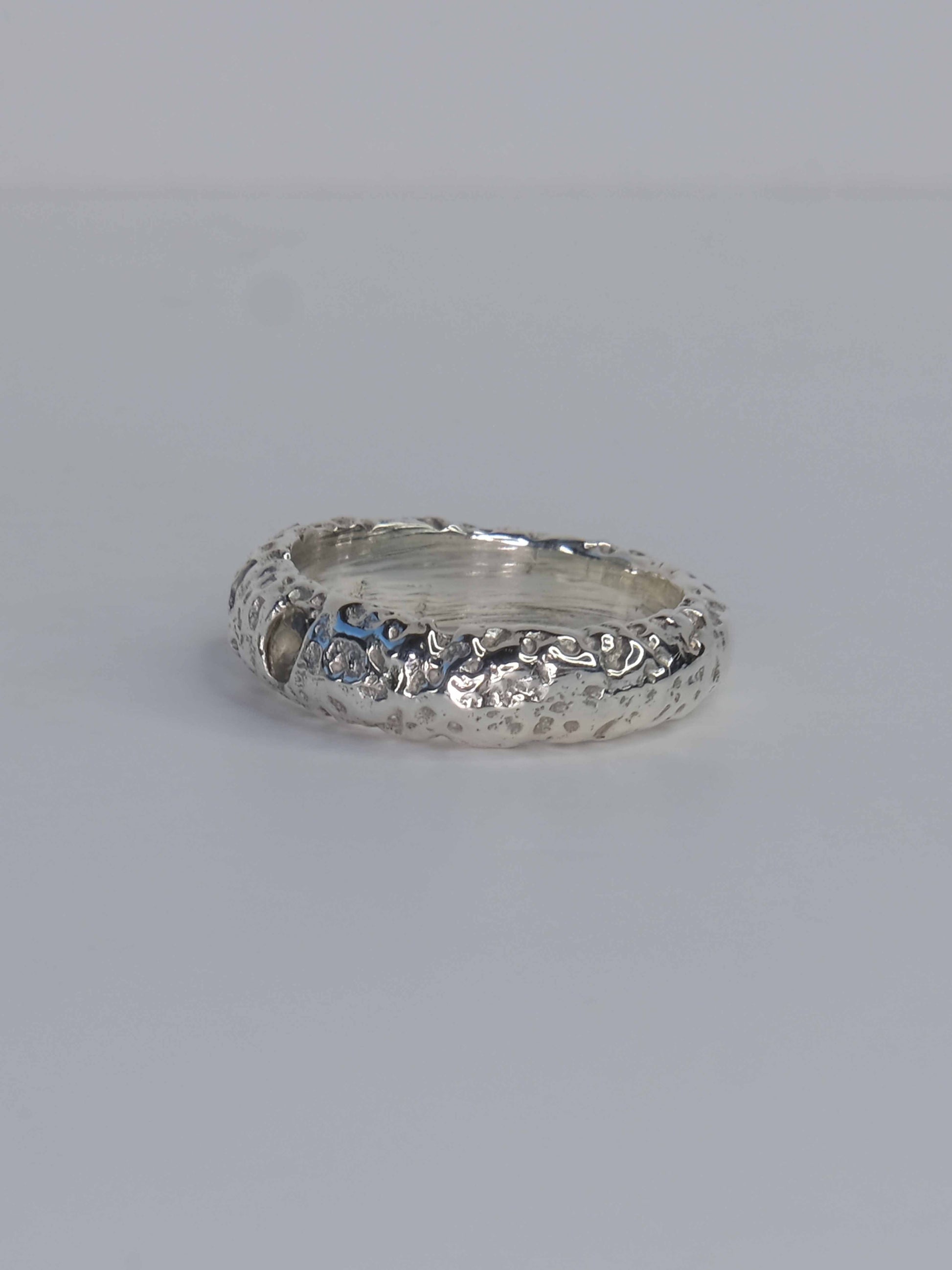 Handgefertigter Ring aus 925 Sterling-Silber strukturierter Oberfläche, durch Sandguss gefertigt, und drei grünen und roten Saphiren – designed und made in Berlin.