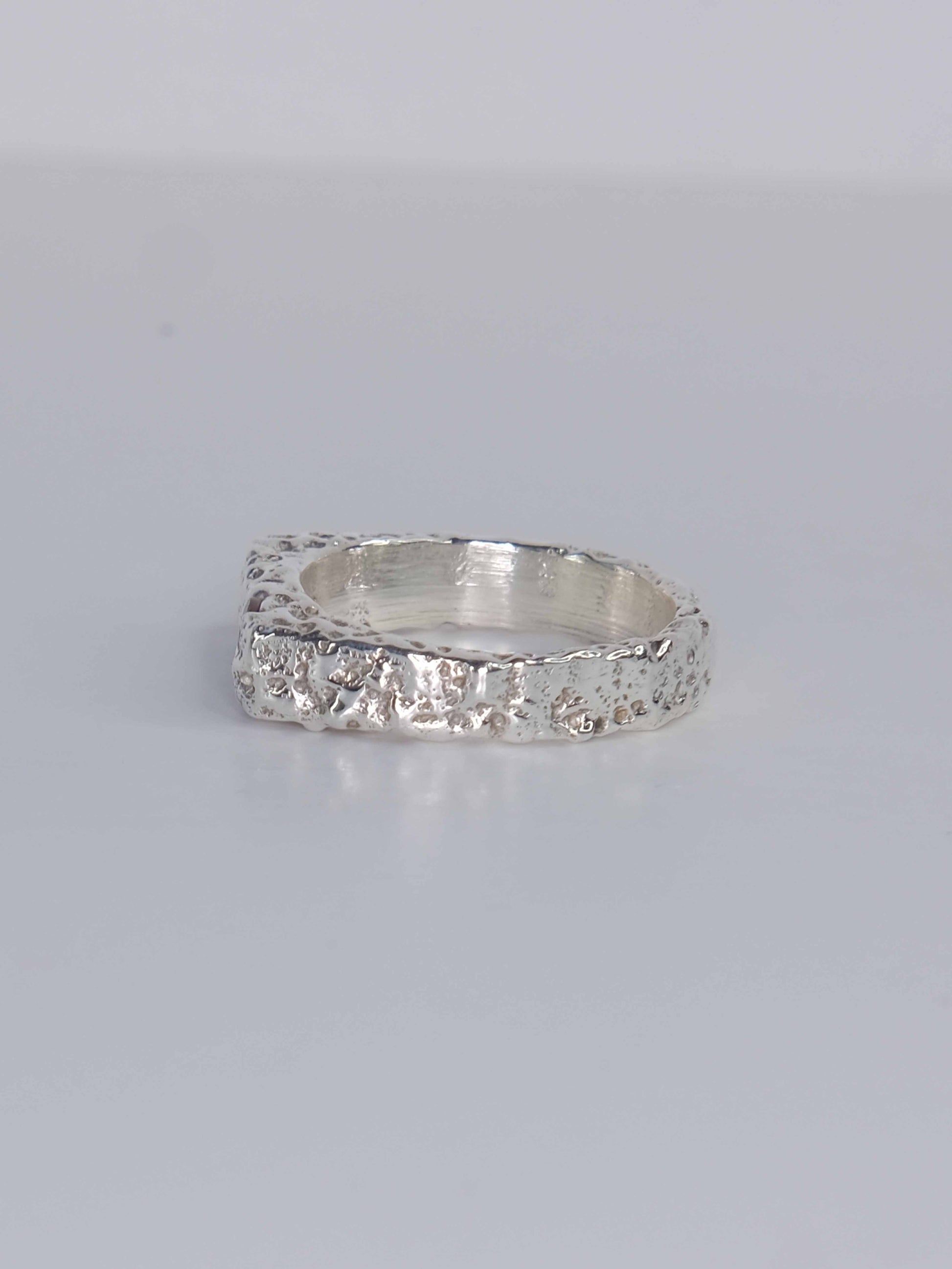 Handgefertigter Dune Siegelring aus 925 Sterling-Silber mit strukturierter Oberfläche in schlanker Form, durch Sandguss gefertigt und mit zwei grünen und auburn braunen Saphiren – designed und made in Berlin.