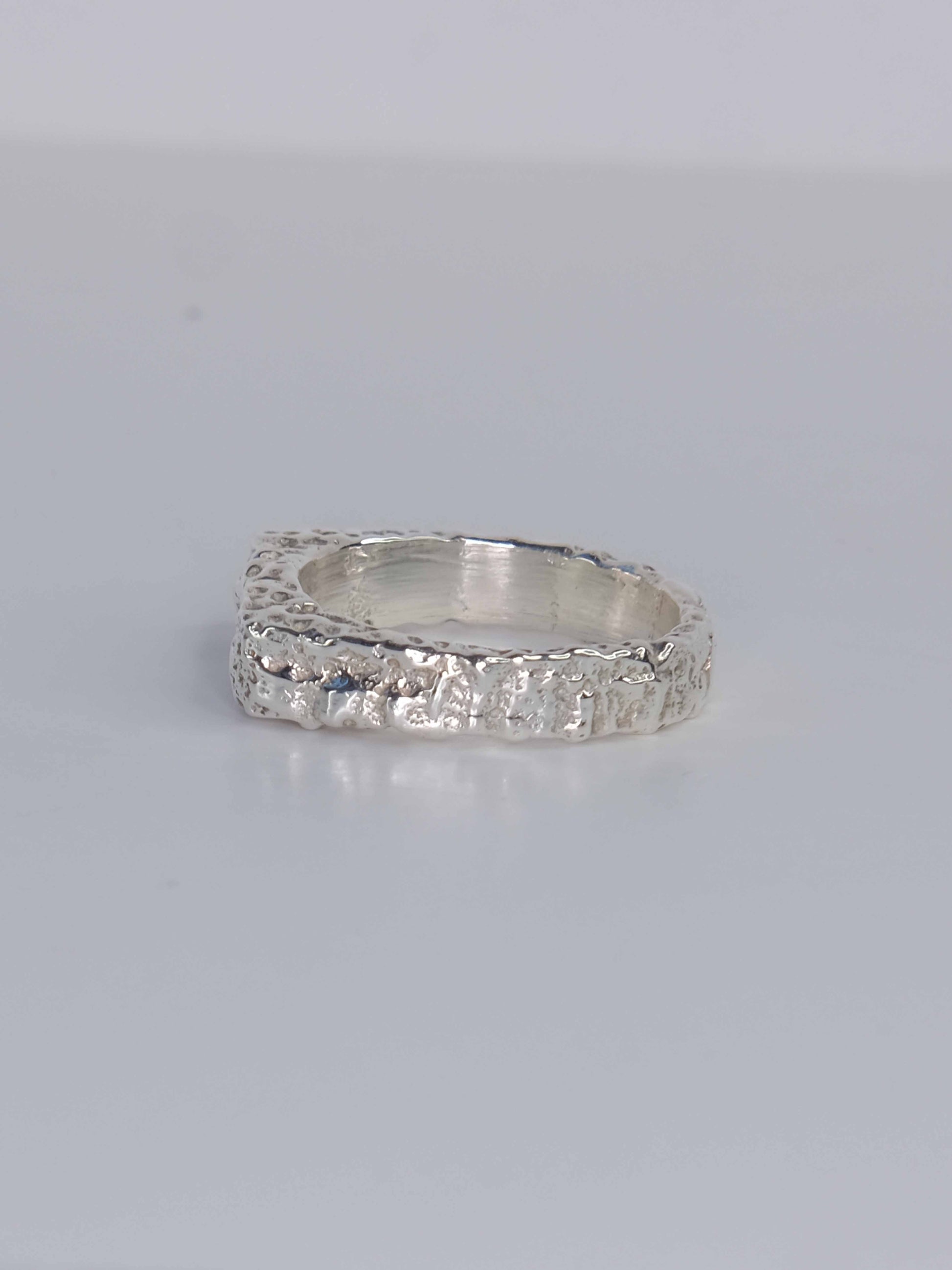 Handgefertigter Dune Siegelring aus 925 Sterling-Silber mit strukturierter Oberfläche in schlanker Form, durch Sandguss gefertigt und mit grünem Saphir – designed und made in Berlin.