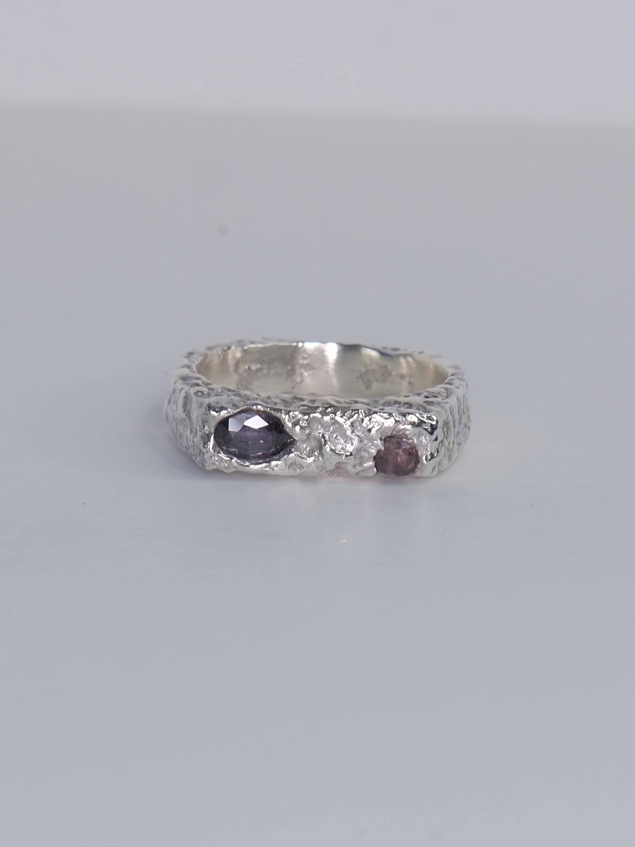 Handgefertigter Dune Siegelring aus 925 Sterling-Silber mit strukturierter Oberfläche in schlanker Form, durch Sandguss gefertigt und mit zwei violett und pink braunen Saphiren – designed und made in Berlin.